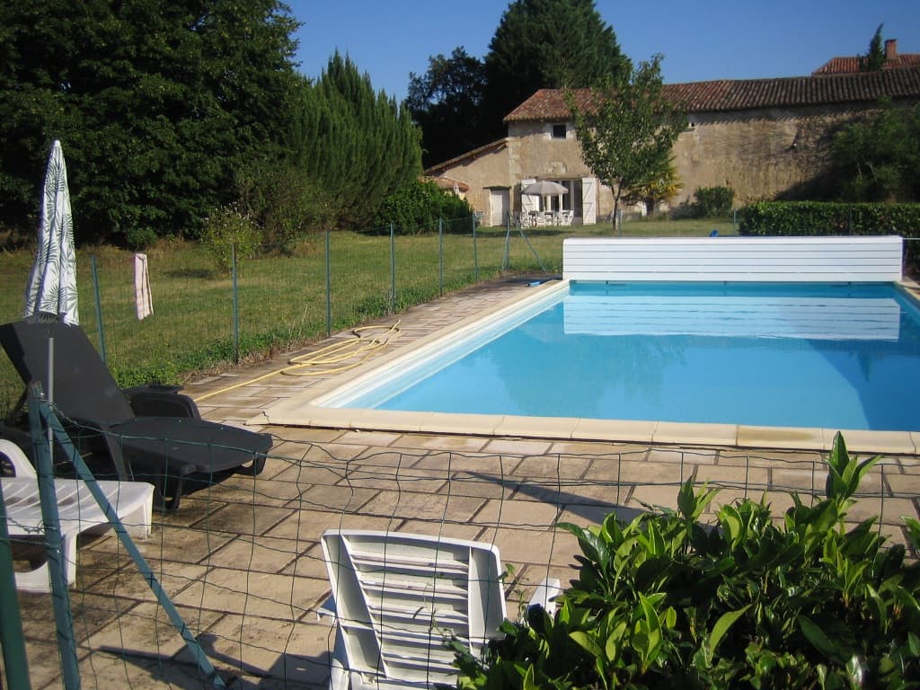 la piscine clôturée et la maison en fond
