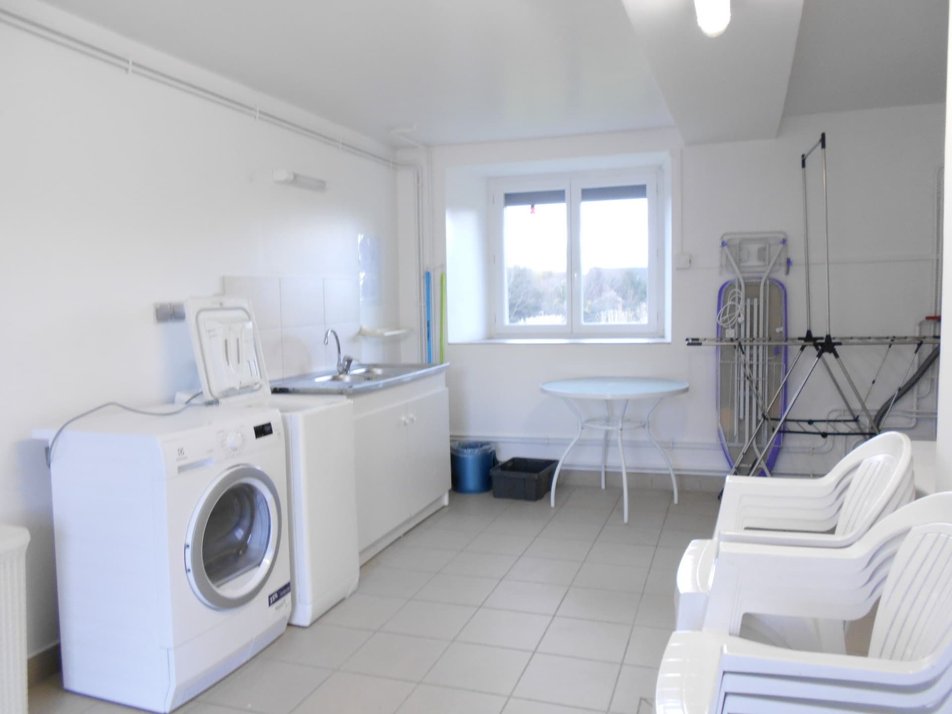 Buanderie avec lave linge,sèche linge, table et chaises d'extérieur. RdC
