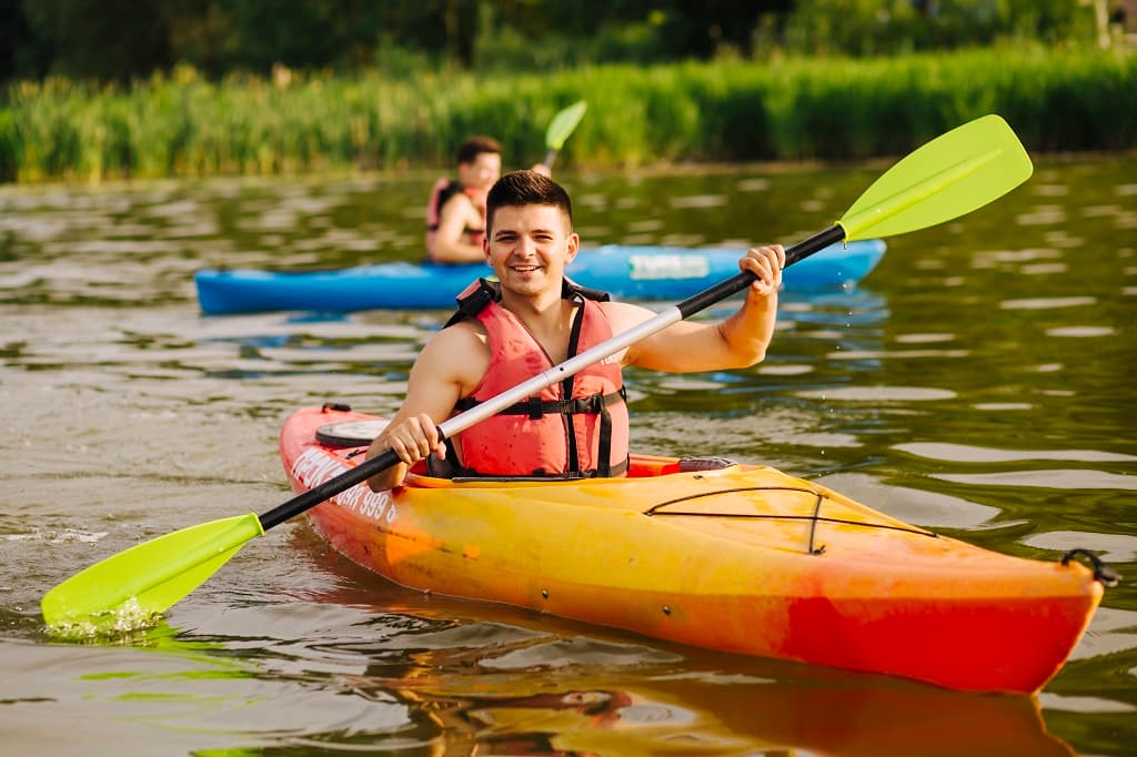 homme-souriant-pagayant-kayak-lac