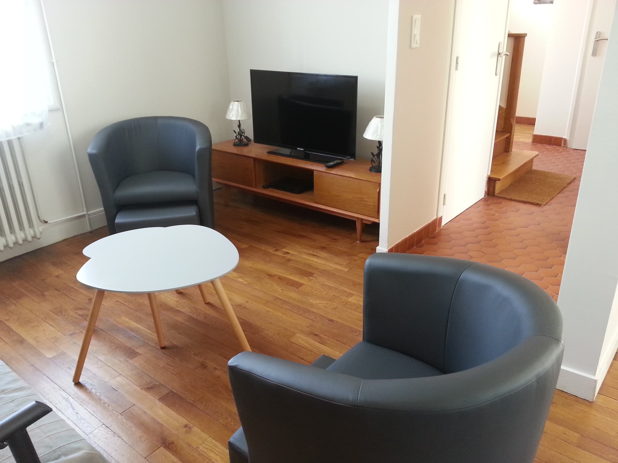 Le salon avec vue sur la 1ère télévision, des poufs doubles et 1 table vintage