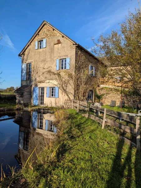 La maison d’hôtes Saisonnée se reflète dans l’ancien bassin naturel, offrant une atmosphère paisible et authentique au cœur du Ségala, à Centrès.