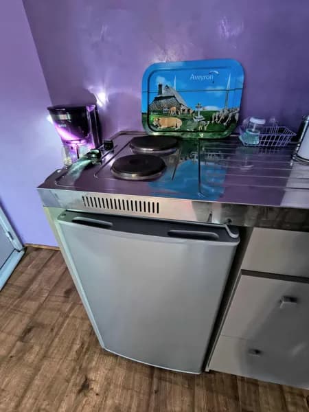 Kitchenette fonctionnelle du gîte Panoramique, équipée de plaques de cuisson, réfrigérateur et cafetière. Un espace pratique pour préparer ses repas en toute autonomie lors d’un séjour en Aveyron.